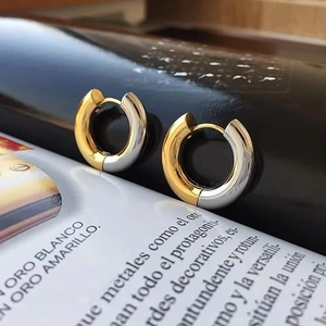 Detail of two-tone gold and silver stainless steel huggie earrings with mirror finish