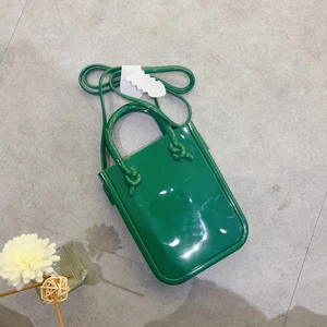 Detailed top view of a green PVC jelly tote bag with knotted handle and long shoulder strap