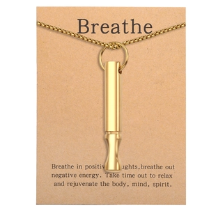 Close-up of golden mindfulness whistle necklace on Breathe positive message card