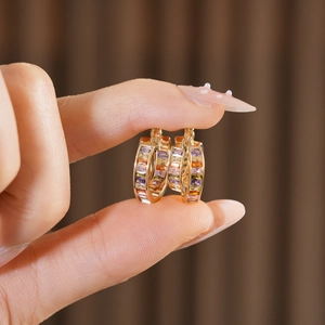 Close-up of vintage square hollow earrings with colorful gemstones worn on the ear