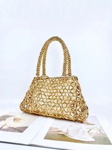 Elegante goldene gewebte Perlenhandtasche mit Innenfutter auf weißem Magazin-Hintergrund