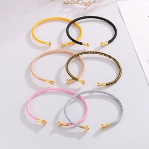 Detail of multi-color woven cuff bracelets with gold-plated ends on a white background