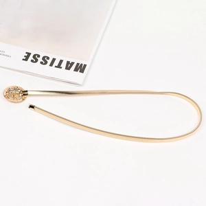 Détail d'une ceinture chaîne dorée élastique avec une boucle ronde ornée de strass
