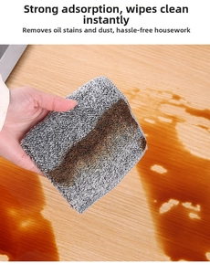 Close-up of thick bamboo charcoal fiber cleaning cloth wiping liquid on wood surface