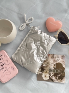 Silver quilted bow pouch with pearl chain tassel and sleek metallic texture finish