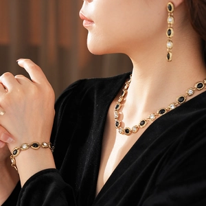 Gros plan d'un ensemble de bijoux vintage dorés avec pierres noires et claires sur modèle