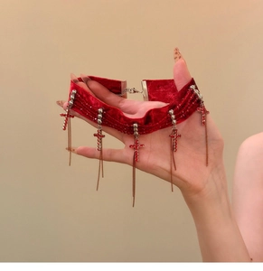 Detail of red velvet choker with crystal cross charms and long golden chain tassels