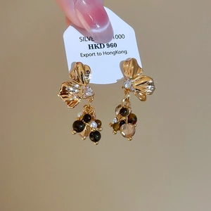 Macro view of gold flower earrings with tiger eye beads and cascading crystals
