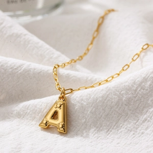 Golden bubble letter A pendant necklace with textured dots on a minimalist link chain