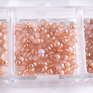 Close-up of pink semi-round pearls in a storage box for DIY nail art and craft