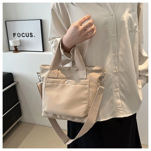Detalle de bolso tote de nailon caqui con bolsillo frontal y correa ajustable cómoda