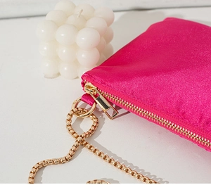 Detail of rose red satin tote bag with premium gold chain and zipper closure