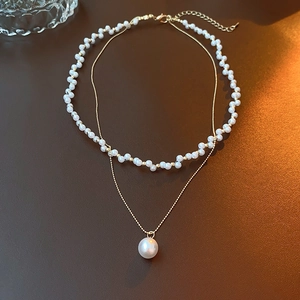 Detail view of double-layer necklace with vintage pearls and golden chain link