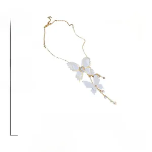 Détail du collier papillon en dentelle douce avec perles et strass sur chaîne dorée