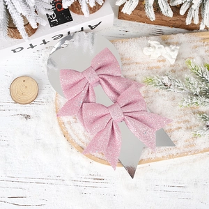 Glittery pink bow christmas ornaments on silver card with festive snowy winter decor