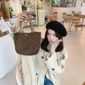 Detailed shot of brown corduroy tote bag with bear print and metal snap button closure