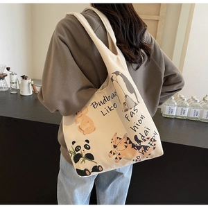 Candid photo of a cream canvas tote bag with animal illustrations worn as a shoulder bag