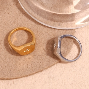 Close-up of gold and silver North Star signet rings with inset crystals on soft felt