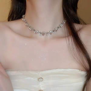 Close-up of diamond heart pearl necklace on collarbone with soft dreamy lighting