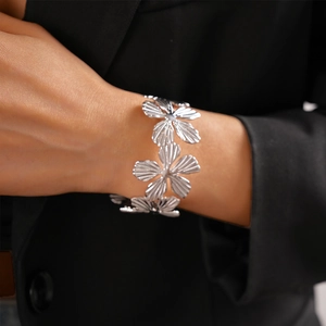 Detailed view of silver flower bracelet with textured petals worn on a model's wrist