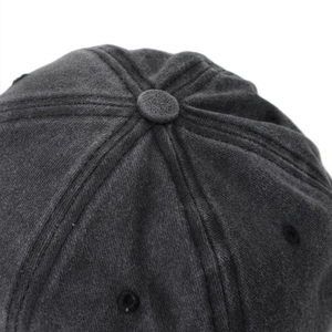 Detail view of the top button and embroidered eyelets on the charcoal denim baseball cap