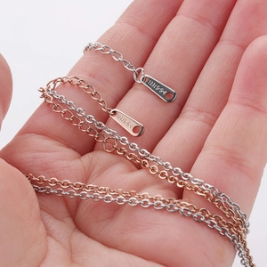 Detail of silver and rose gold stainless steel chains showing the S.STEEL hallmark clasp