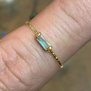 Close-up of gold geometric square ring with light teal rectangle gemstone and hammered texture