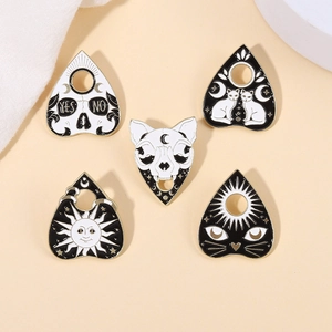 Macro shot of dark gothic enamel brooches with skull, cat, and sun motifs on fabric