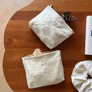 Beige floral jacquard cotton makeup bag and hair tie set on a wooden table