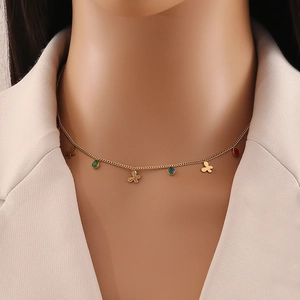 Golden clover necklace with colorful red blue and green gemstone charms on a model