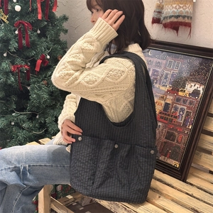 Close-up of a large plaid tote bag with three front snap pockets for daily commuting