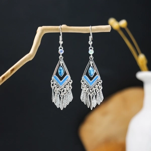 Macro detail of Bohemian rhombus earrings with blue beads on a decorative branch