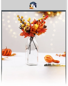 Halloween centerpiece with artificial pumpkins, berries, and maple leaves in a glass vase