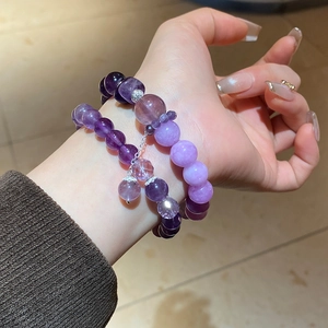 Detailed view of natural amethyst beaded bracelet with silver charm on a wrist