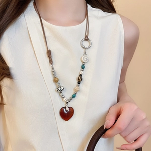 Detailed view of large red heart pendant with ethnic beads on a long sweater necklace