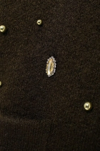 Close-up of amber gemstone and clear crystals on brown beaded knit cardigan
