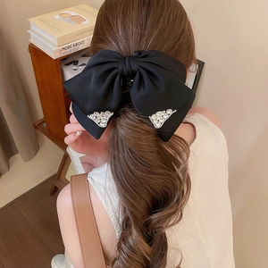 Detail of elegant black satin bow hair claw with sparkling rhinestones for hair styling