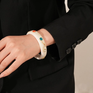 Detail of white marble acrylic cuff bangle with colorful rhinestones on a black suit sleeve