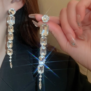 Close-up of square cut crystal tassel earrings showing sparkling light reflections on model