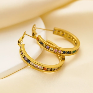 Gold hoop earrings with multicolored zircon crystals on light beige silk background
