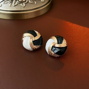 Dettaglio di orecchini a bottone vintage bianco e nero con texture a spirale dorata