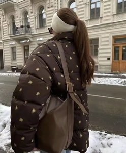 Detail view of floral puffer jacket with drawstring hood and leather shoulder bag