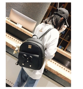 Rear view of a black PU leather backpack with a bow decoration on a model