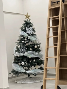 Close-up of artificial green Christmas tree with silver bows and white mesh ribbon