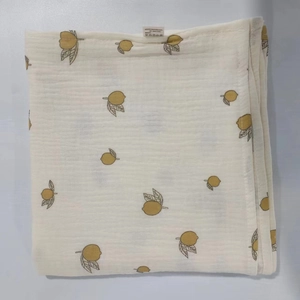 Detail of soft cotton muslin baby swaddle with yellow lemon and grey leaf prints