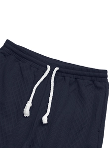 Detail of dark blue knit shorts with white drawstring and textured diamond pattern