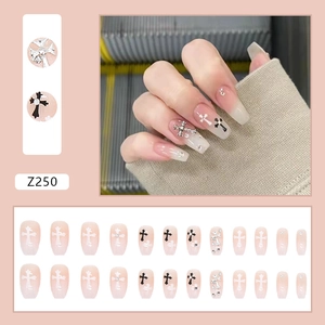 Long nude press-on nails with black cross patterns and silver glitter accents