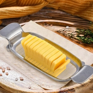 Stainless steel butter slicer tool on a wooden tray with fresh yellow butter slices