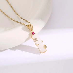 Macro shot of gold-plated pendant with white resin, red zircon, and leaf motifs