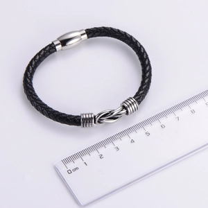 Dettaglio del bracciale in pelle nera intrecciata con chiusura magnetica e scala
